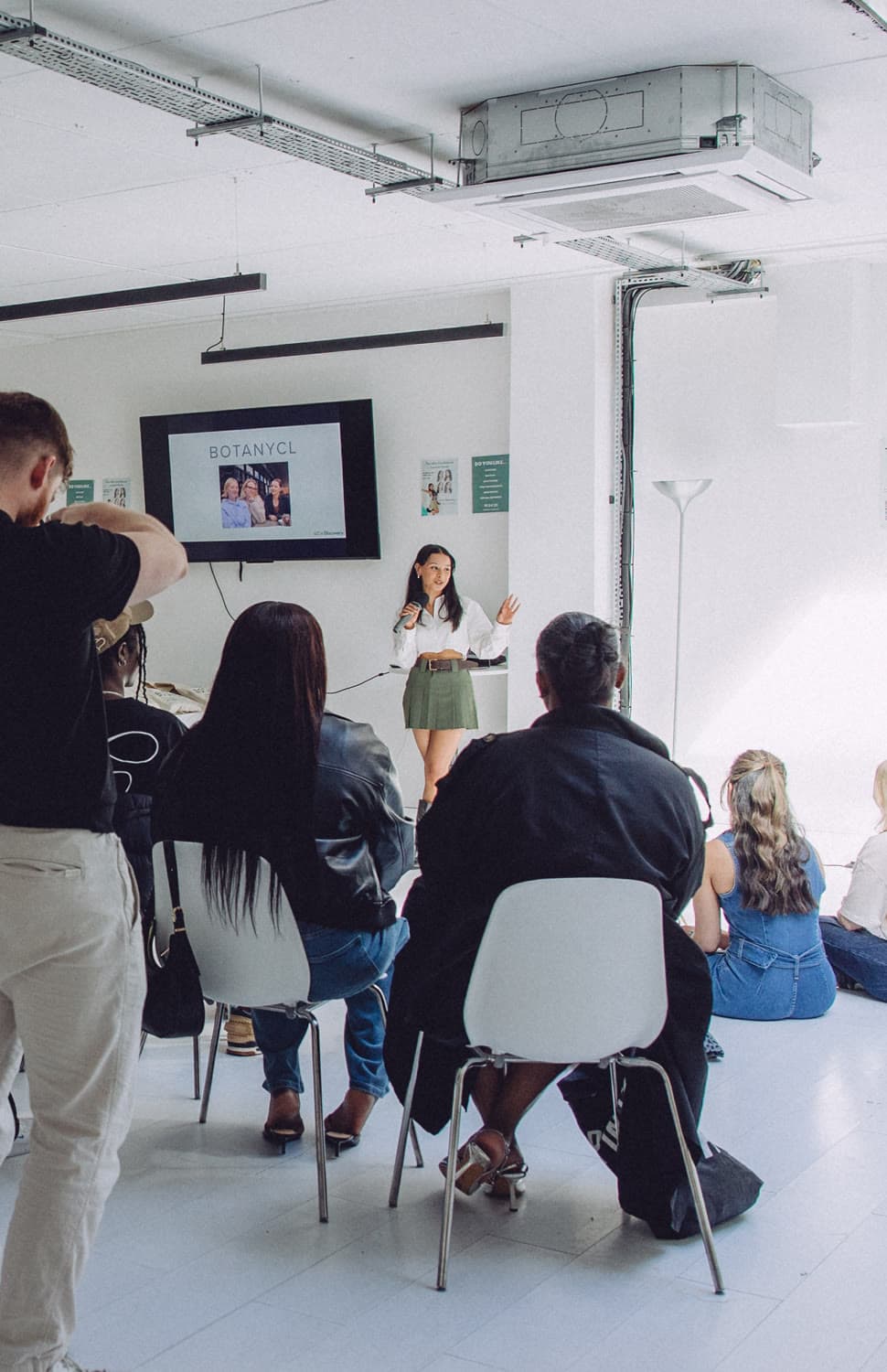 Kiara presenting on stage to a seated audience at a live event