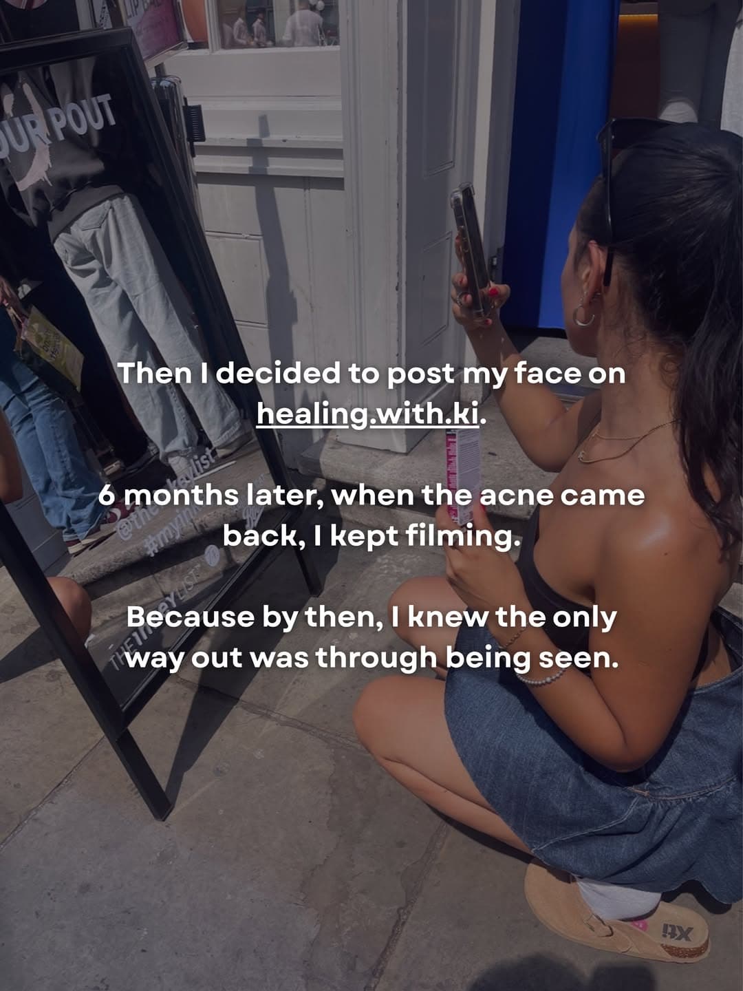 Kiara crouched outside a London shop window, filming a story on her phone.